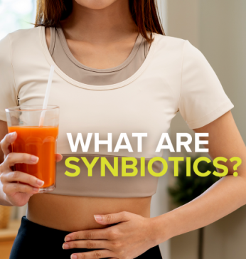 Woman holding stomach and drink with text: What are Synbiotics?